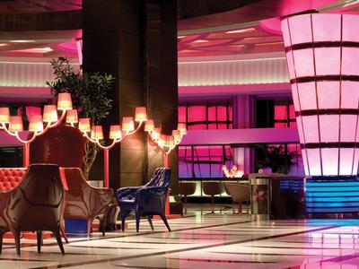 Moderner Hotel-Lobby mit pinker Beleuchtung, bequemen Sesseln und stilvollen Lampen.