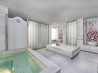 Modernes, helles Spa mit großem Whirlpool und Liege im luxuriösen Ambiente.