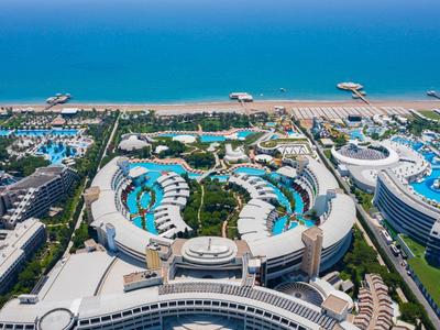 Luftaufnahme eines großen Strandresorts mit mehreren Pools, grünen Gärten und direktem Zugang zum Meer.