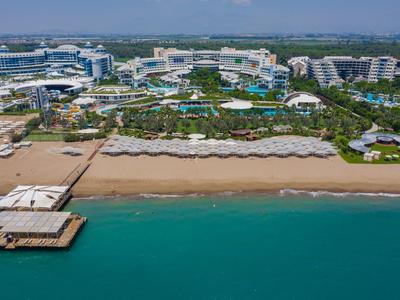 Luxuriöses Strandresort mit Pools, Sonnenschirmen, Sandstrand und klarem Meerwasser.