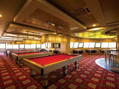 Ein stilvoller Billardraum mit roten Tischen und gemütlicher Beleuchtung in einem Hotel.