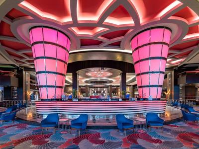 Modern gestaltete Hotelbar mit pink beleuchteten Säulen und farbenfroher Teppichgestaltung.