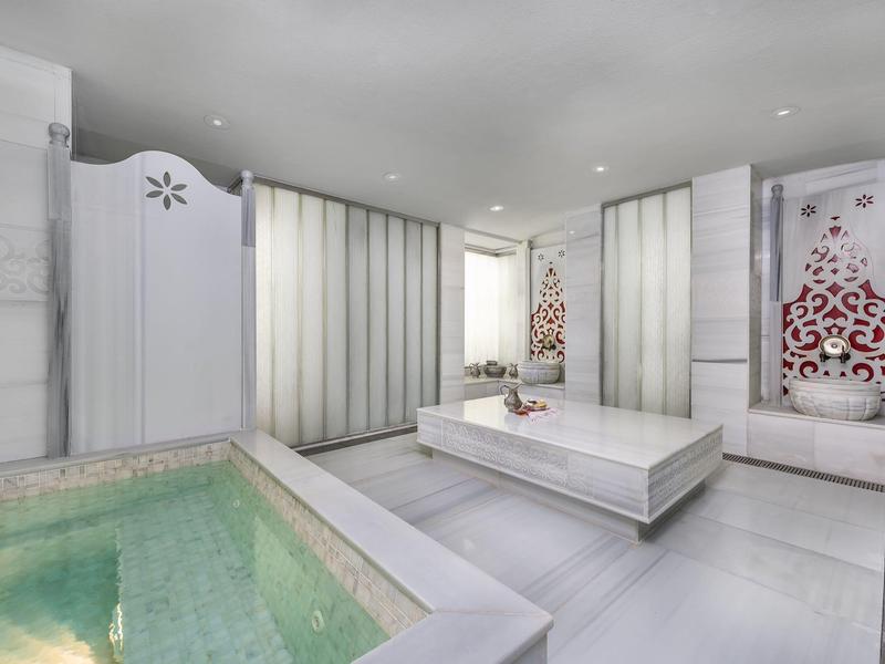 Modernes, helles Spa mit großem Whirlpool und Liege im luxuriösen Ambiente.