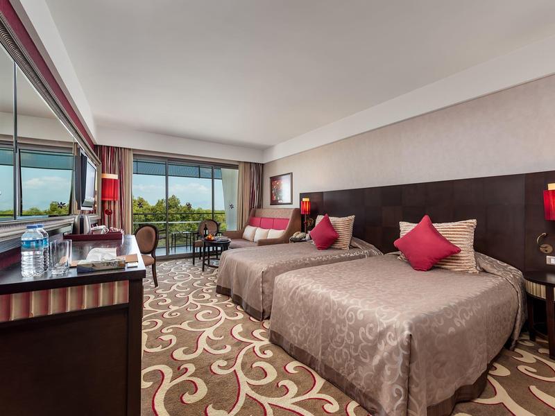 Helles Hotelzimmer mit zwei Betten, Teppichboden und Meerblick durch große Fenster.