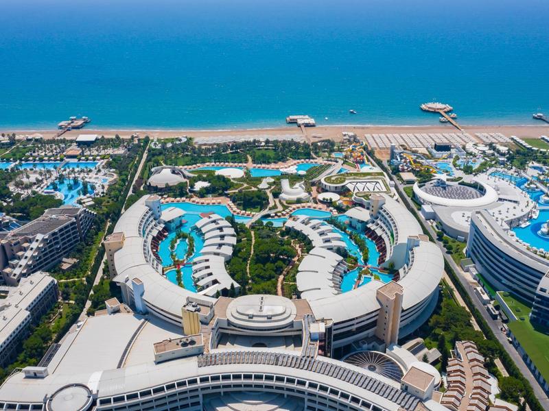 Luftaufnahme eines großen Strandresorts mit mehreren Pools, grünen Gärten und direktem Zugang zum Meer.