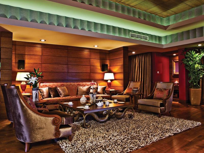 Elegantes Hotelwohnzimmer mit Holzvertäfelung, gemütlichen Sesseln und Teppichboden.