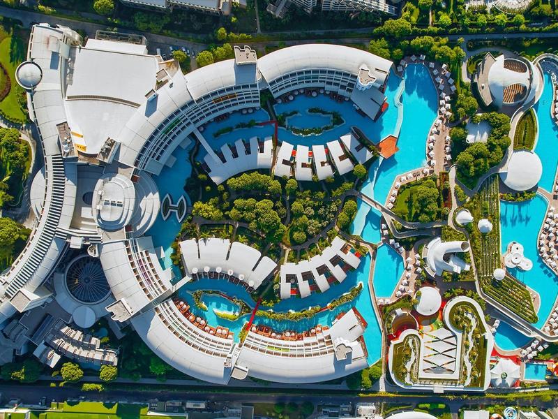 Luftaufnahme eines großen Resorts mit Poollandschaften und begrünten Bereichen.