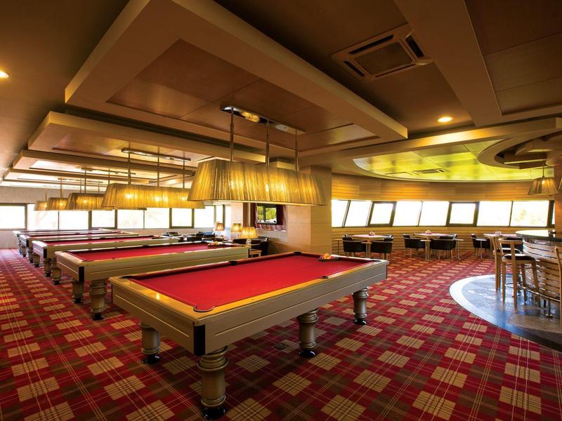 Ein stilvoller Billardraum mit roten Tischen und gemütlicher Beleuchtung in einem Hotel.