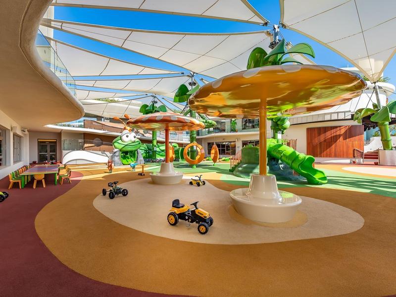 Bunter moderner Kinderspielplatz mit Rutschen, Sandbereich und Sonnensegeln im Freien.