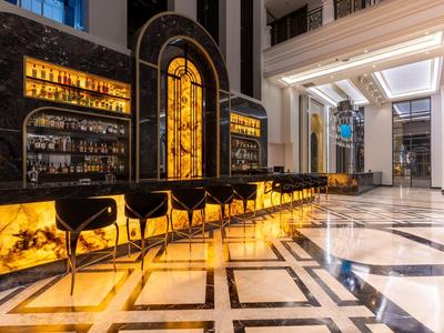 Bar elegante de hotel con barra iluminada de ónix y asientos negros en ambiente lujoso.