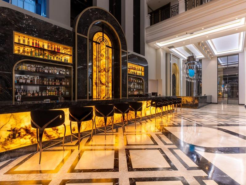 Bar elegante de hotel con barra iluminada de ónix y asientos negros en ambiente lujoso.