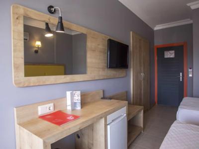 Habitación de hotel con muebles de madera, espejo grande, TV y dos camas.