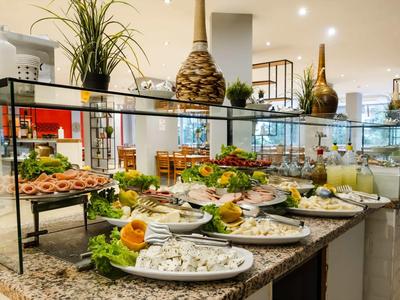 Hotel buffet with assorted cold dishes and decorative plants in the dining area.