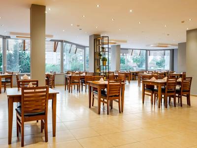 Bright, spacious restaurant with wooden chairs and large windows allowing ample daylight.