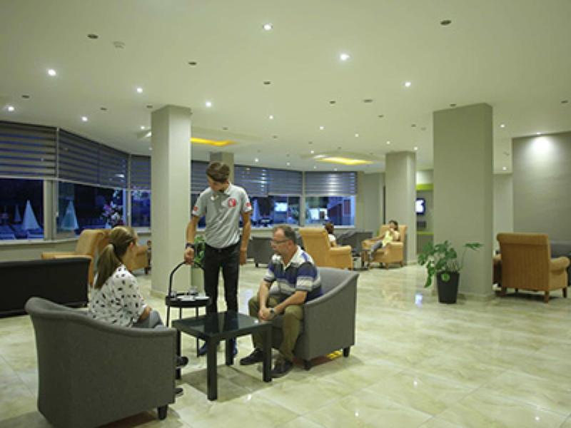 Hotel lobby with modern furniture, three guests, and bright lighting.