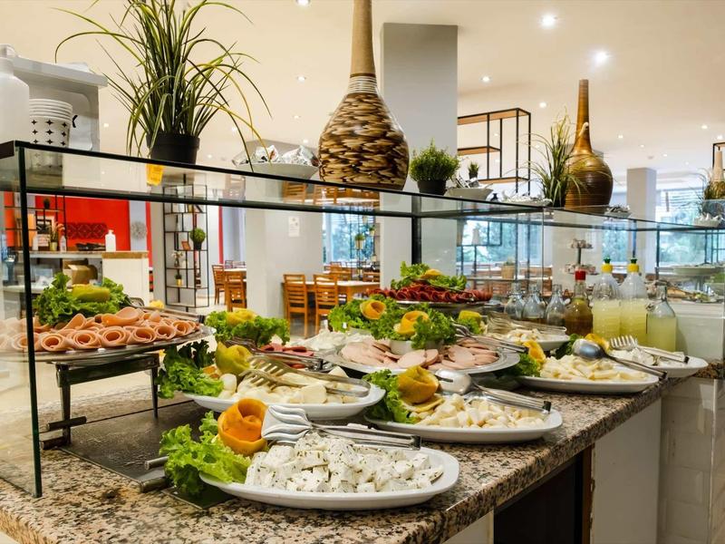 Hotel buffet with assorted cold dishes and decorative plants in the dining area.