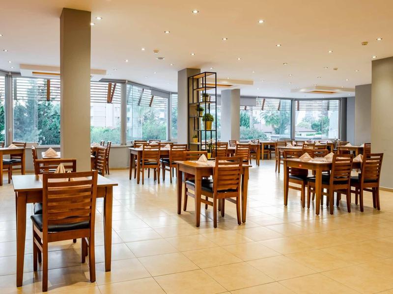 Bright, spacious restaurant with wooden chairs and large windows allowing ample daylight.