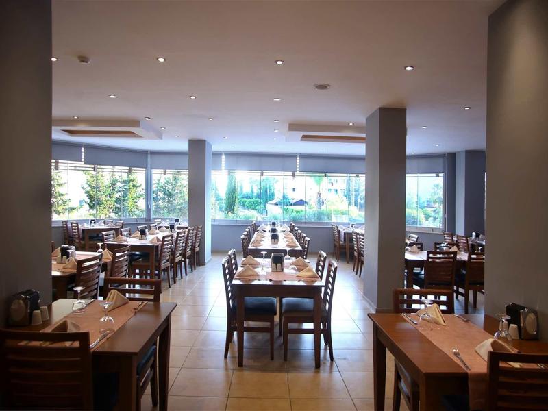 Bright restaurant with wooden tables and chairs, large windows, and a modern atmosphere.