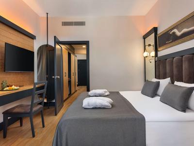 Modernes Hotelzimmer mit großem Bett, Schreibtisch, Fernseher und stilvoller Beleuchtung.