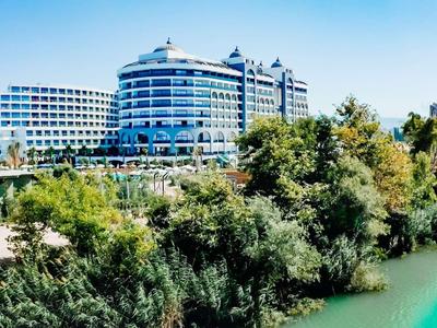 Hôtel moderne avec façades courbes au bord d'une rivière, entouré d'arbres.