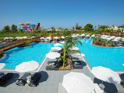 Gran piscina al aire libre con tumbonas y sombrillas en un complejo hotelero en un día soleado.