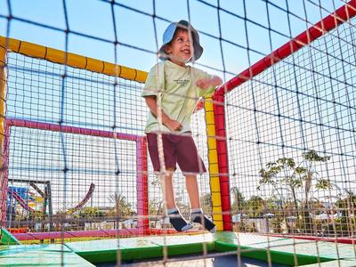 Bambino che gioca su un trampolino con rete di sicurezza all'aperto in una giornata di sole.