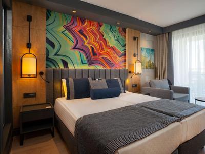 Camera d'hotel moderna con letto grande, arte murale colorata e aree salotto accoglienti.