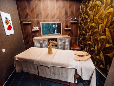 Una stanza per massaggi elegantemente arredata con un lettino da trattamento e un'illuminazione calda e accogliente.