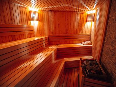 Interno di una sauna con rivestimento in legno, panche e stufa per sauna.