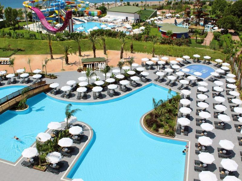 Grand piscine extérieure avec parasols blancs et toboggan dans un complexe hôtelier.
