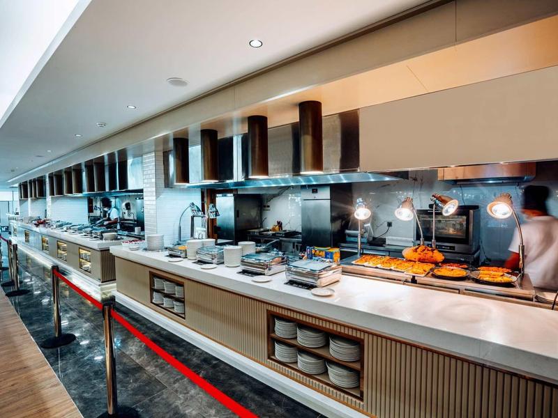 Cuisine d'hôtel moderne avec appareils en acier inoxydable, grand espace de travail et buffet.