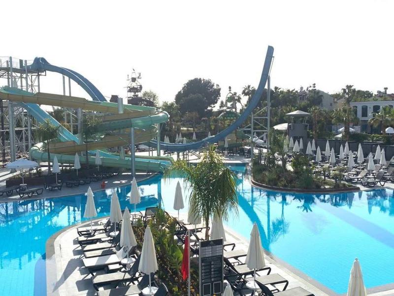 Grand piscine extérieure avec toboggans et transats dans une station hôtelière.