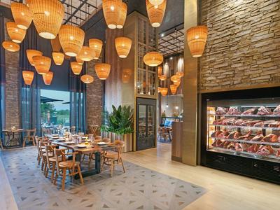 Restaurante moderno con luz cálida, muebles de madera y una gran vitrina de vinos.