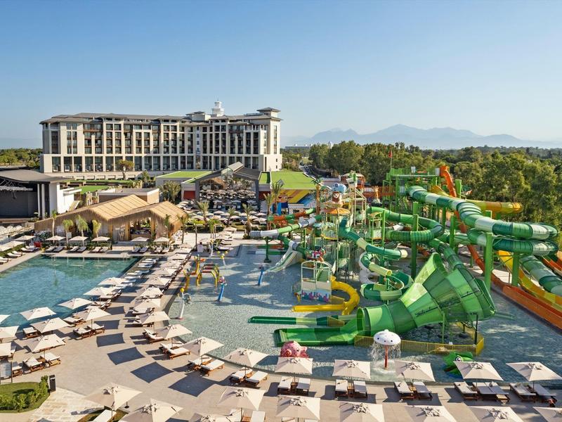 Hotel con gran piscina al aire libre, toboganes de agua y muchas tumbonas con sombrillas.
