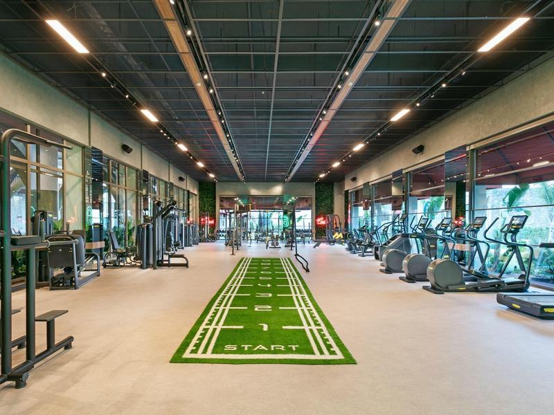 Gran gimnasio moderno con equipos y pista de carrera en el centro.