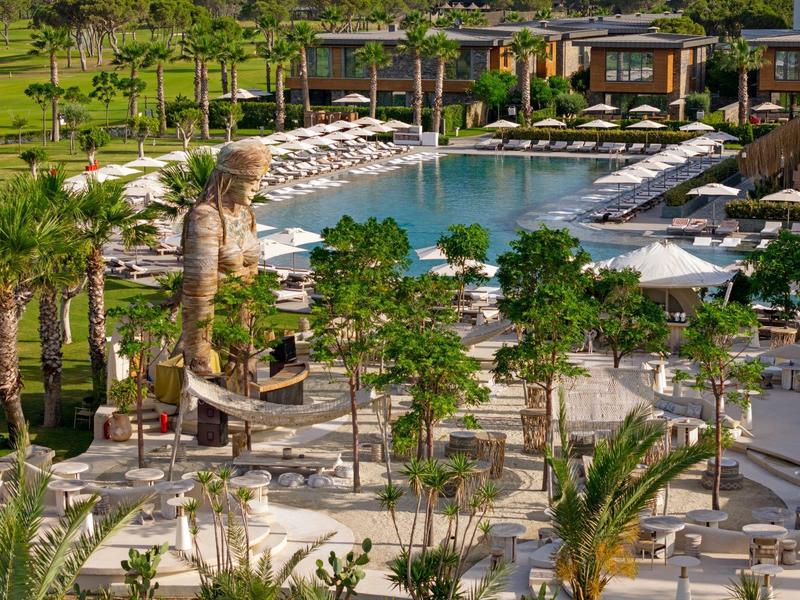 Amplia piscina rodeada de palmeras y tumbonas en un resort tropical soleado