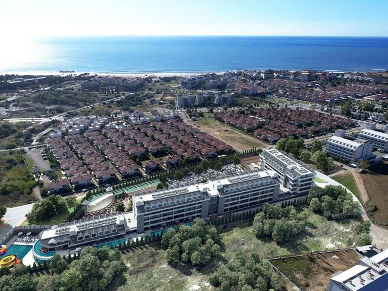 Widok z lotu ptaka na hotel nad morzem z osiedlem mieszkalnym w tle pod czystym niebem.