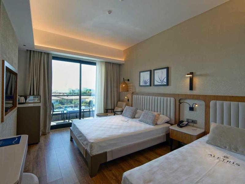 Jasno urządzone pokoje hotelowe z dwoma łóżkami i dużym oknem z widokiem na zewnątrz.