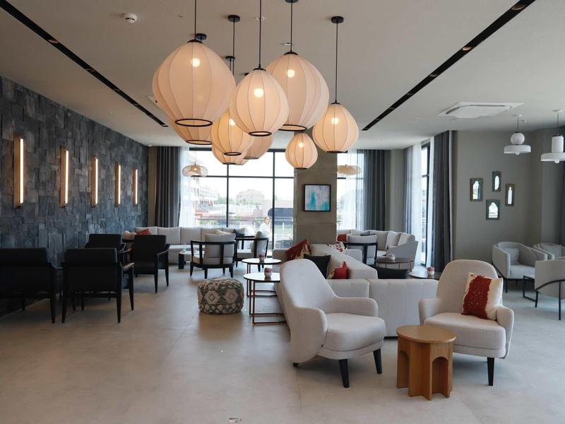 Nowoczesny salon hotelowy z białymi fotelami i dużymi okrągłymi lampami.