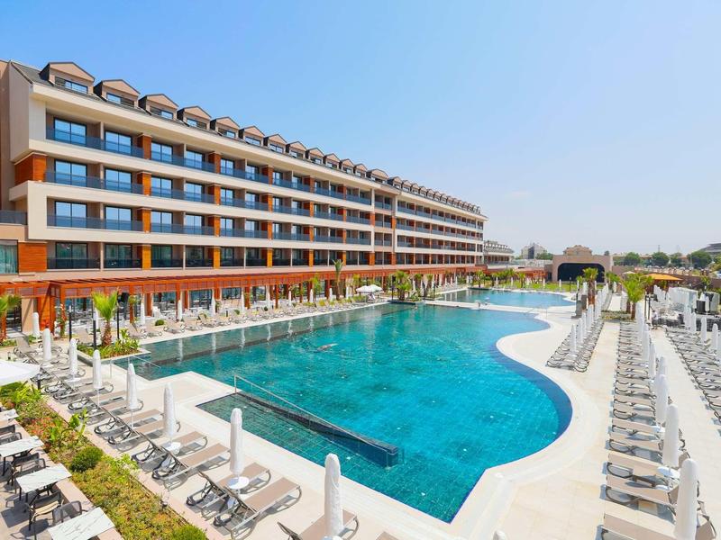 Nowoczesny kompleks hotelowy z dużym basenem na zewnątrz i wieloma leżakami pod czystym niebem.