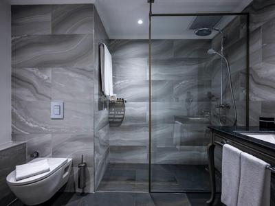 Salle de bain moderne avec douche à l'italienne et toilettes suspendues, murs en marbre gris.
