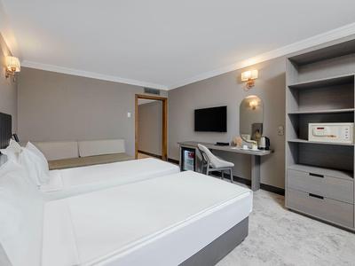 Chambre moderne avec lit double, télévision, bureau et placard gris.