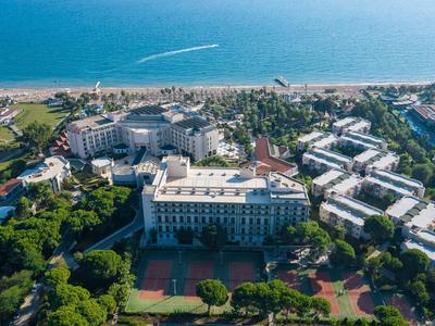 Grand complexe hôtelier avec piscine au bord de la mer et jardins verdoyants.