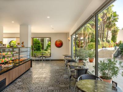 Salon lumineux avec tables, chaises et comptoir près d'une grande baie vitrée donnant sur un jardin.