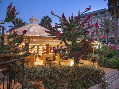 Padiglione illuminato in un giardino dell'hotel di notte con fiori e palme.