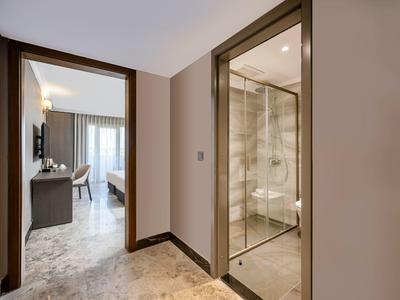 Entrée d'une chambre d'hôtel avec une salle de bain vitrée et un sol en marbre.