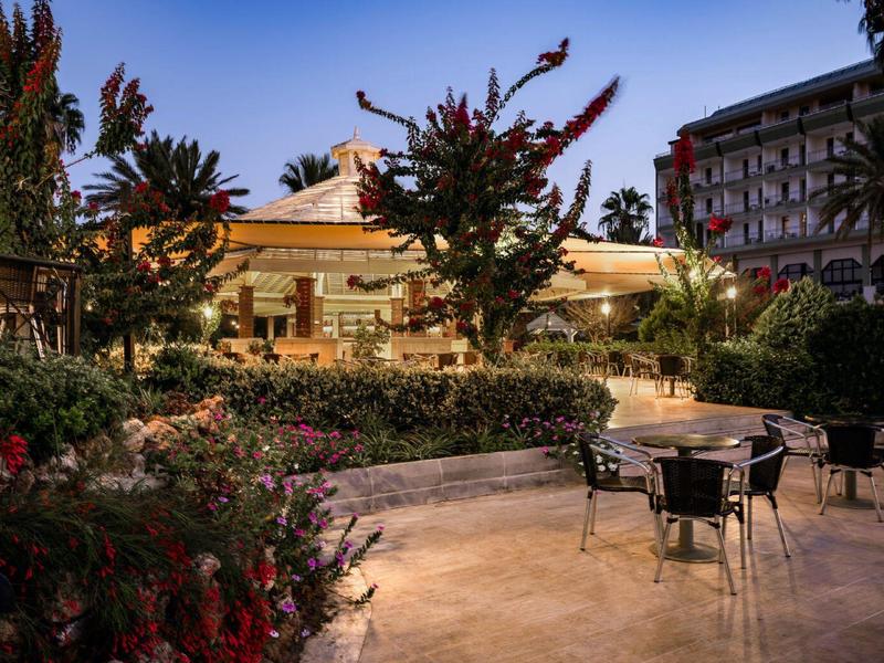Terrasse extérieure avec chaises et tables dans un jardin éclairé au crépuscule.