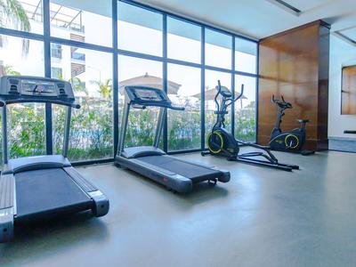 Moderní fitness zařízení v světlé tělocvičně s velkými okny a výhledem na přírodu.