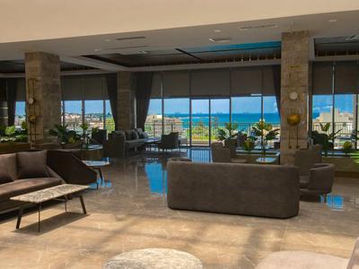 Salon d'hôtel moderne avec vue sur la mer à travers de grandes baies vitrées.