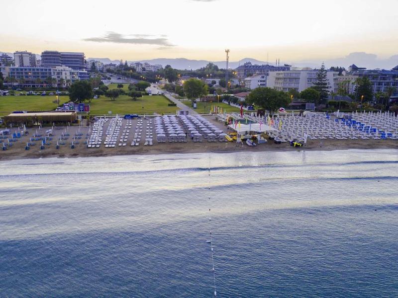 Vue sur une plage avec des rangées de parasols et de chaises longues au coucher du soleil.